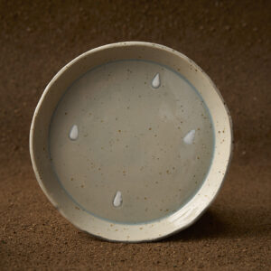 Prato en gres moteado claro con debuxos de gotas con engobe. Esmaltado en esmalte transparente azulado