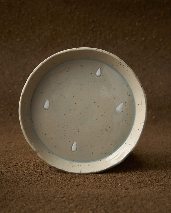 Prato en gres moteado claro con debuxos de gotas con engobe. Esmaltado en esmalte transparente azulado