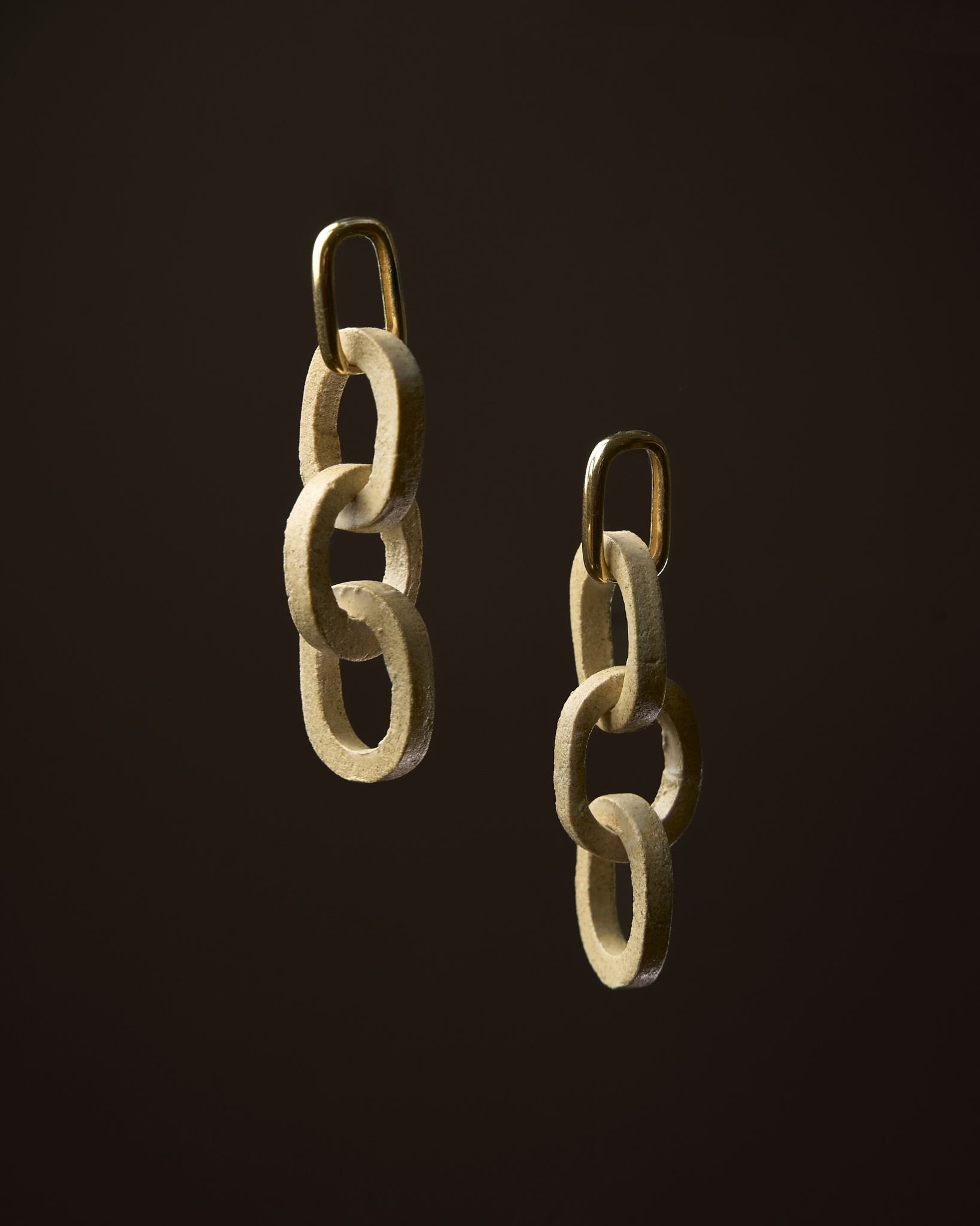Pendentes Elos en gres crema mate con peche en ouro sobre fondo escuro